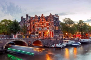 Online Amsterdamse grachtenpanden met boten op de voorgrond fotobehang Steden | Architectuur