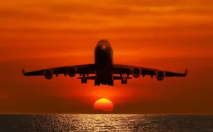 Best Passagiersvliegtuig boven de zee bij zonsondergang fotobehang Transport
