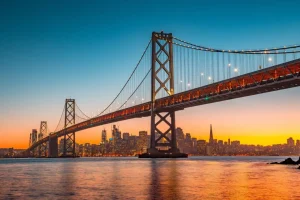 Online San Francisco-Oakland Bay Bridge in de avond fotobehang Architectuur